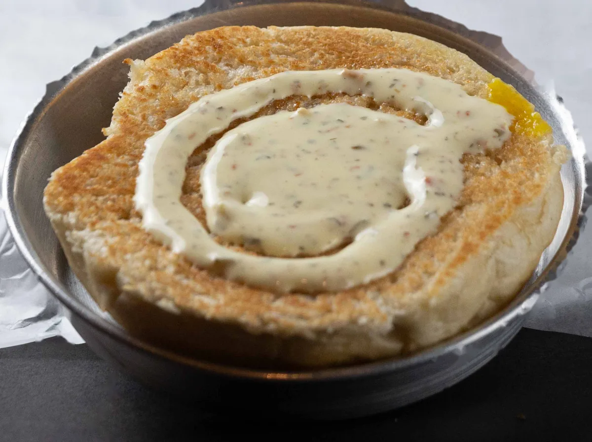 Mayonesa picosita servida en espiral sobre un pan tostado, en un bol de acero